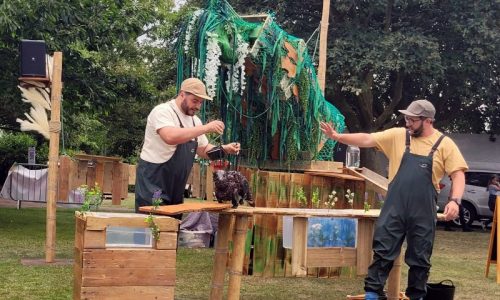 Oscar the Otter interacting with a performer in yellow and green