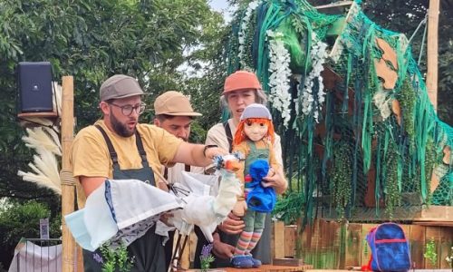 Lyra, holding a blue plastic bag, talking to Hercules the heron.